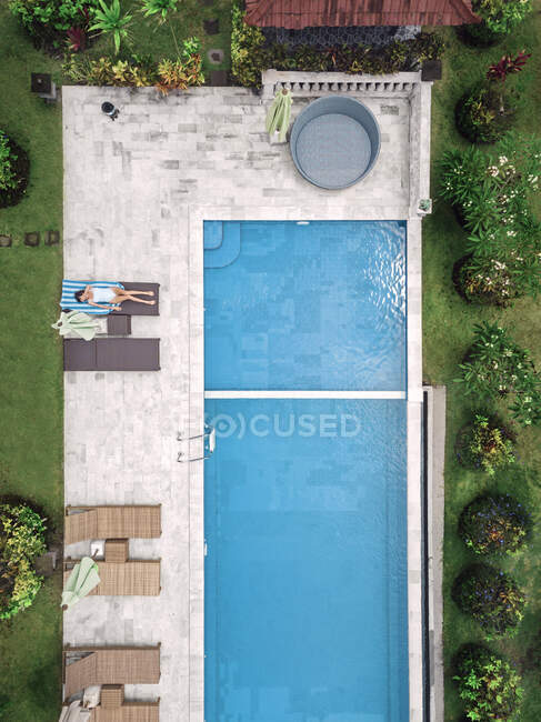 Вид зверху на повітря жінки, що розслабляється навколо басейну у вихідні — стокове фото