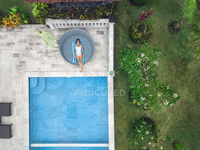Вид зверху на повітря жінки, що розслабляється навколо басейну у вихідні — стокове фото