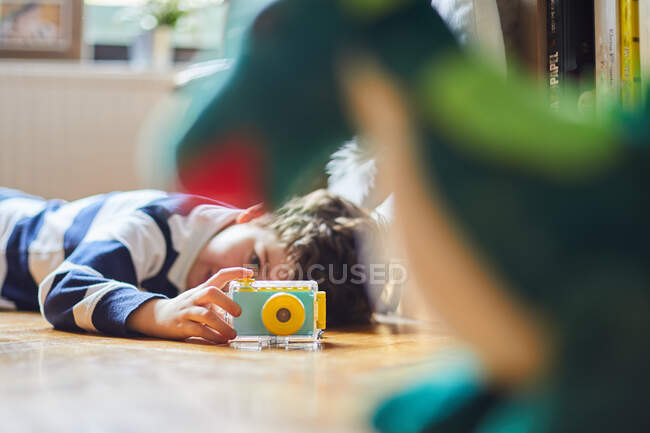 Un niño toma fotos de sus juguetes con su cámara - foto de stock