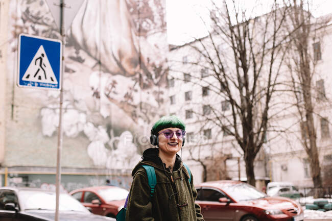 Portrait of happy hipster listening music in headphones walking in city — Stock Photo