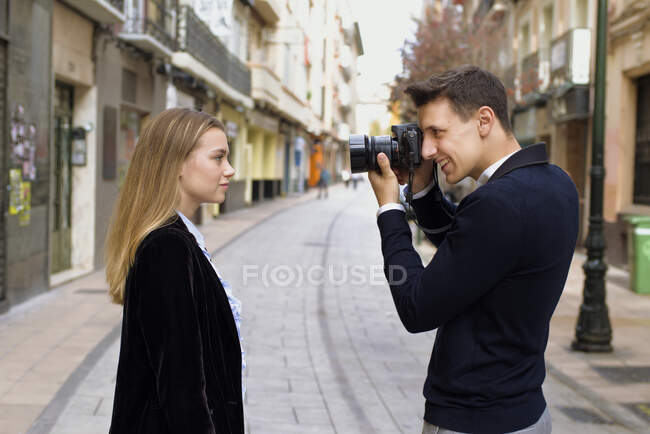 Молодий чоловік фотографує свого друга на вулиці європейського міста. — стокове фото