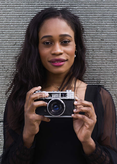 Head portrait of a young African-American woman posing with a camera — Stock Photo
