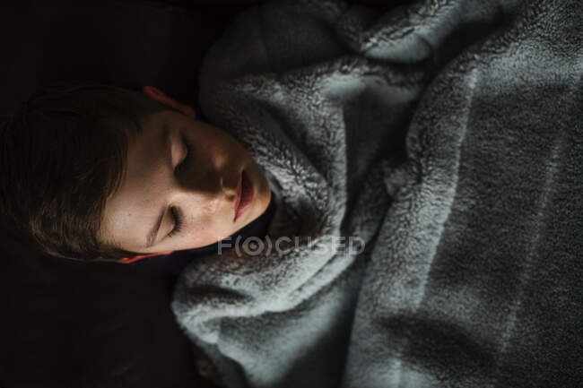 Adolescente chico acogedor y cubierto de manta - foto de stock