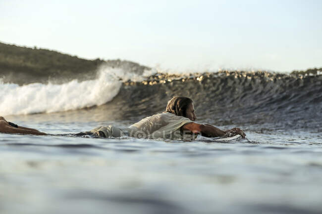 Surfer in sea at sunset, Lombok, Indonesia — Stock Photo