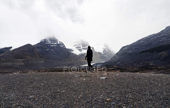 Hombre caminando solo en la cresta rocosa de la montaña - foto de stock