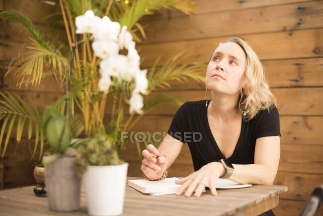 Una chica profundamente pensada mientras escribe en su diario. - foto de stock