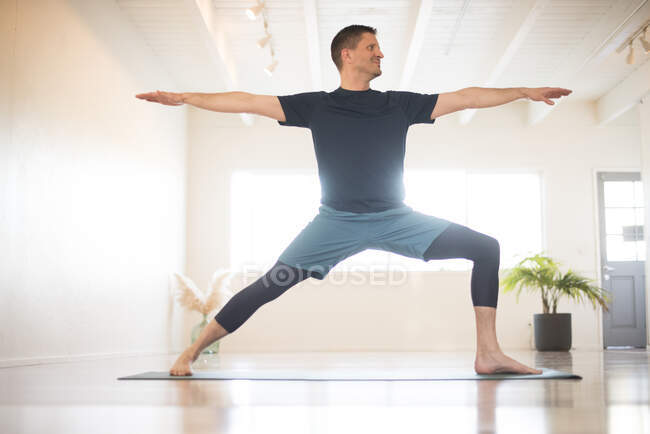 Un ragazzo in Warrior 2 posa durante la pratica dello yoga. — Foto stock