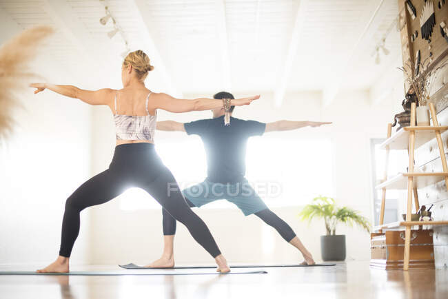 Una coppia in guerriero 2 posa durante lo yoga. — Foto stock