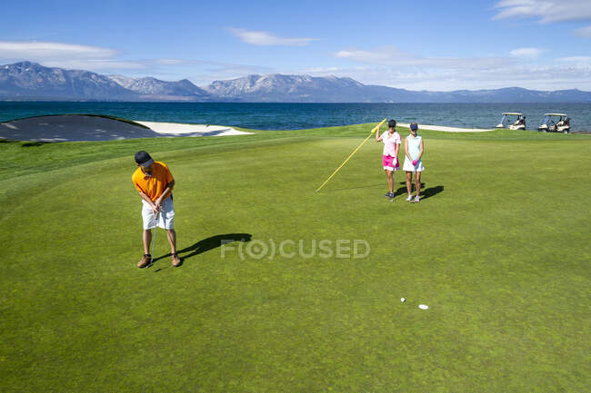 Three people playing golf at Edgewood Tahoe in Stateline, Nevada. — Stock Photo