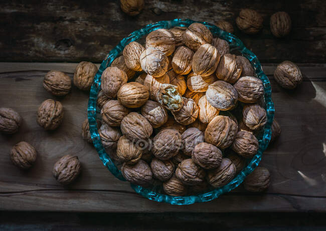 Walnuts in glass bowl on a dark wooden background. — Stock Photo