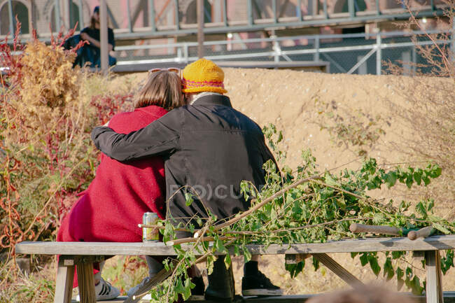 Una pareja se sienta y se abraza al aire libre en un día soleado de otoño - foto de stock