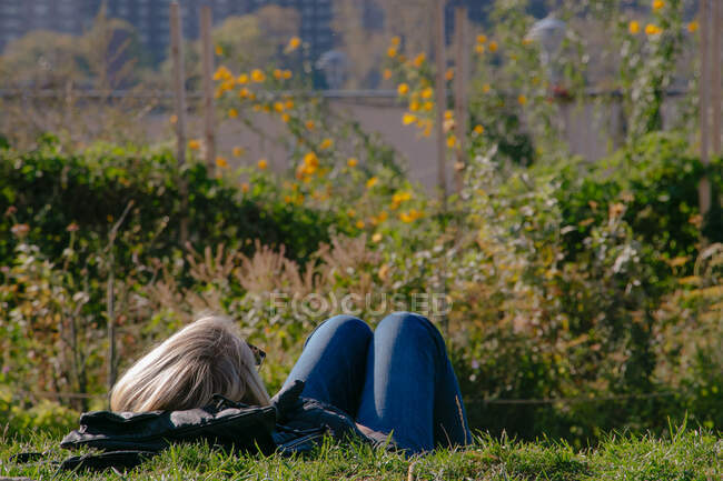 Jeune femme se relaxant dans un parc par une journée ensoleillée à Brooklyn, New York — Photo de stock