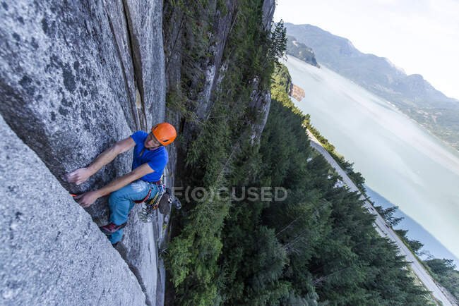 Jeune homme grimpant sur le rocher dans la forêt — Photo de stock