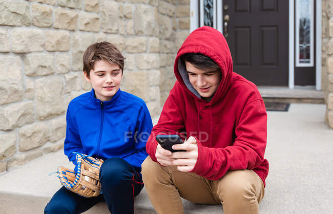 Two teenage boys sitting and talking on the front steps of a house. — Stock Photo