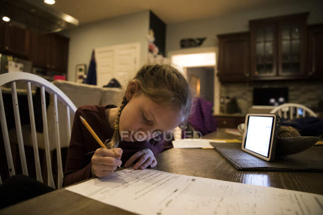 Close-in Vista de la joven en la mesa de la cocina haciendo trabajo escolar - foto de stock