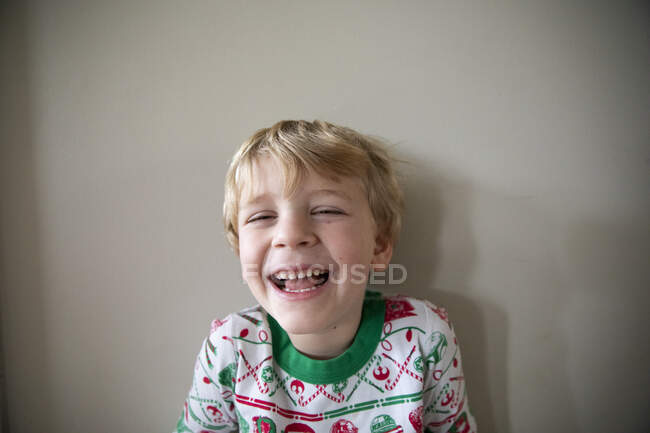 Gros plan Portrait de garçon rieur en pyjama de Noël rouge et vert — Photo de stock