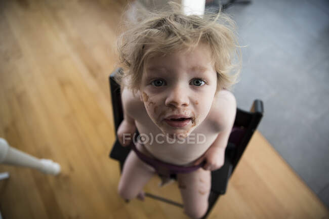 Messy Faced Toddler Sits in High Chair and Looks Up Into Camera — Stock Photo