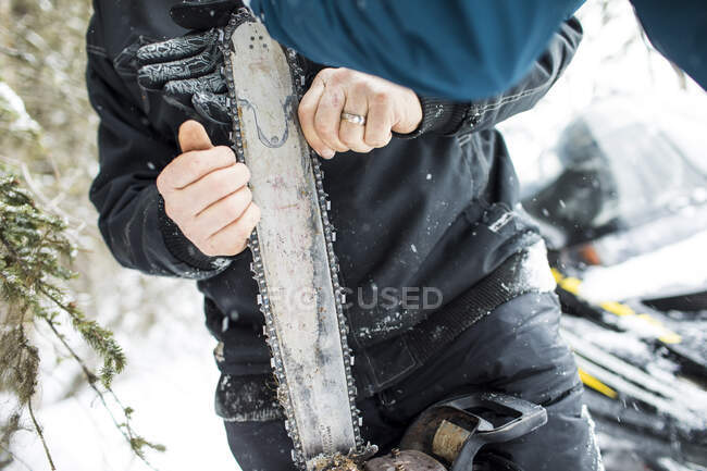 Arborist fixing chain on chainsaw outdoors. — Stock Photo