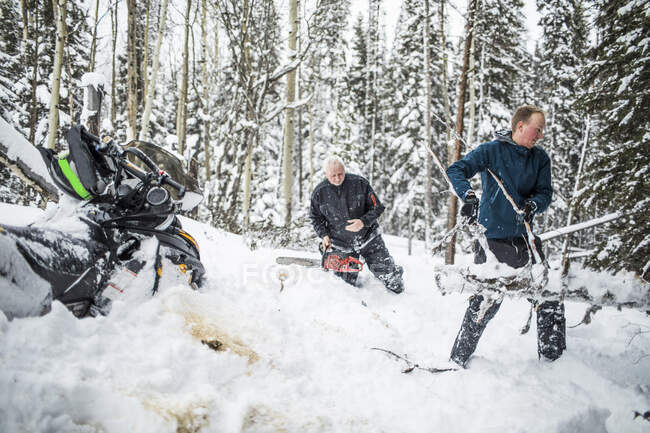 Pai e filho limpando trilhas enquanto snowmobiling. — Fotografia de Stock