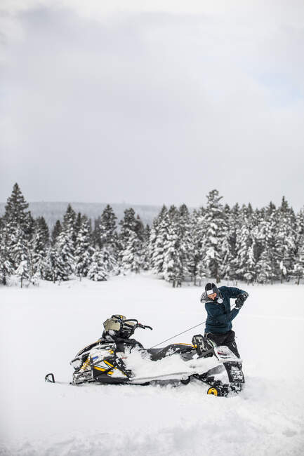Snowmobiler usa cabo de tração para iniciar sua máquina em condições de inverno. — Fotografia de Stock