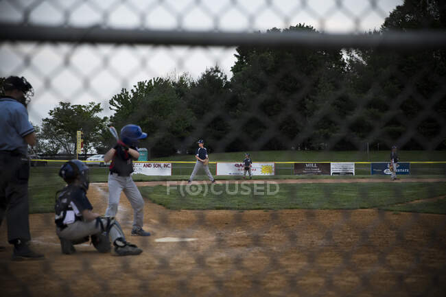 Wide rear view of a teen boy at bat during the baseball game — Stock Photo