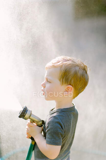 Маленький маленький хлопчик грає з садовим шлангом — стокове фото