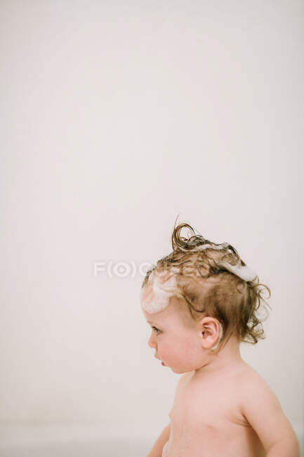 Ребенок в ванне с мыльными волосами в профиле — стоковое фото