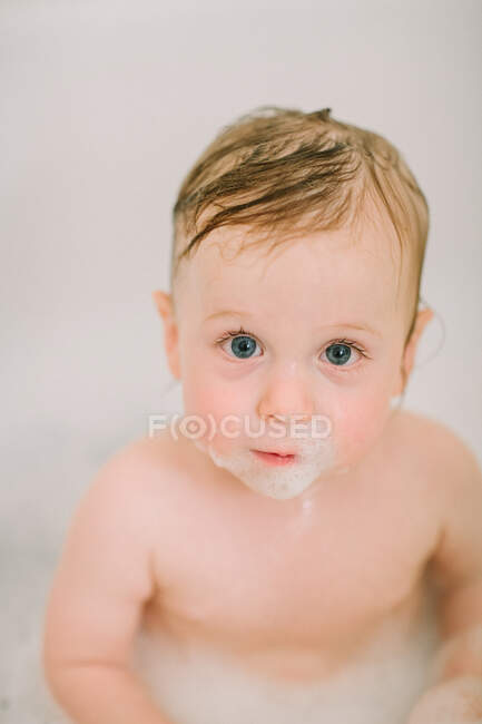 Gros plan du bébé dans la baignoire avec des bulles sur le visage — Photo de stock