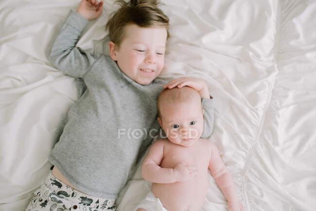 Grand frère et sa petite sœur nouveau-née se blottissant sur le lit — Photo de stock