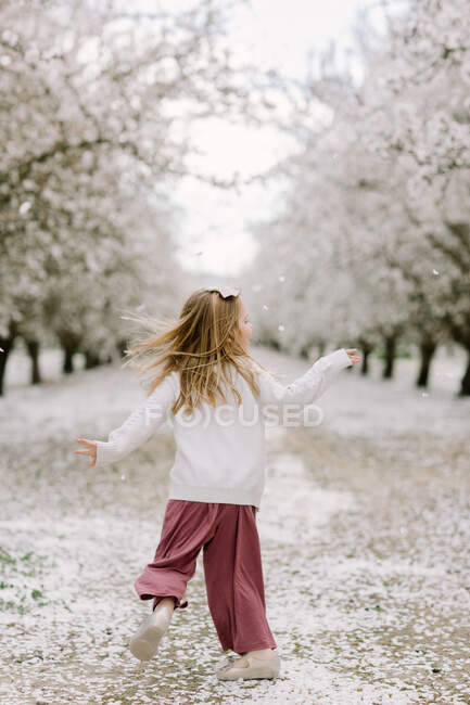 Preschool girl dancing in an almond orchard — Stock Photo