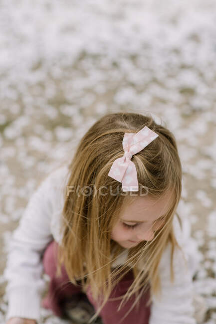 Девочка из детского сада смотрит вниз на землю снаружи — стоковое фото