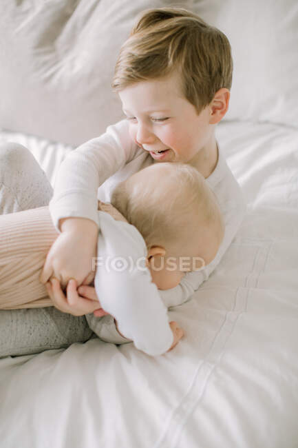 Bambino ragazzo e sorellina giocare su letto a casa — Foto stock