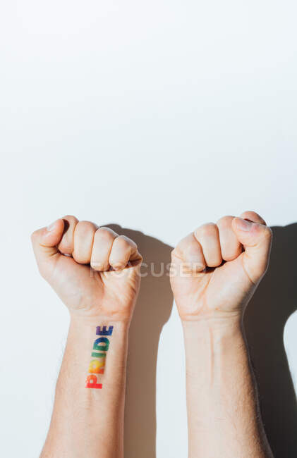 Gay chico de la mano con un tatuaje que dice orgullo y esmalte de uñas. - foto de stock