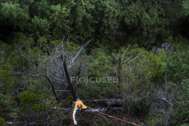Young man climbing the rope on a trail in the mountains — Stock Photo