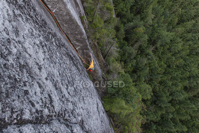 Jovem escalando a corda em uma trilha nas montanhas — Fotografia de Stock