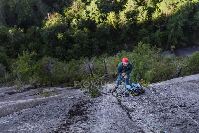 Молодой человек карабкается по веревке по тропе в горах — стоковое фото