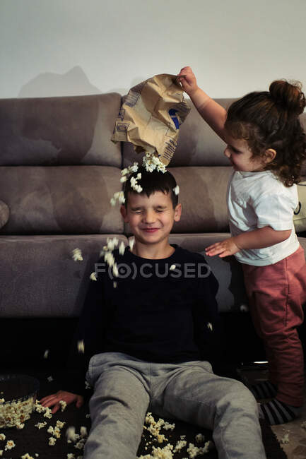 Siblings watching a home movie while eating popcorn — Stock Photo