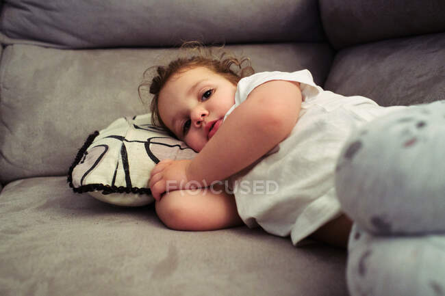 Маленька дівчинка дивиться телевізор, що спить на дивані — стокове фото