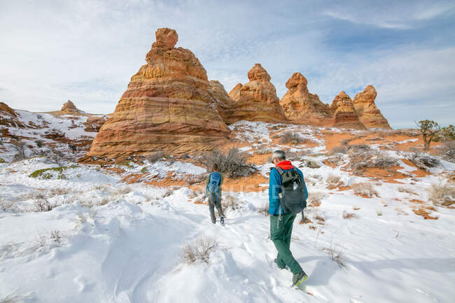 Hikers heading towards snowy Cottonwood Cove in South Coyote Buttes — Stock Photo