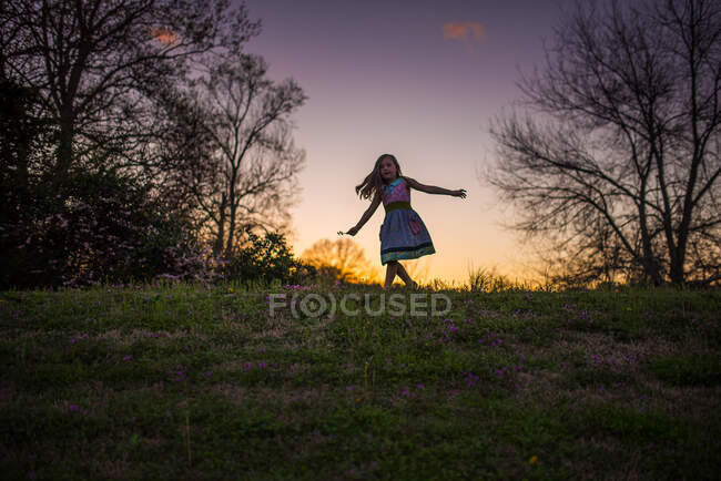 Kleines Mädchen tanzt Sonnenuntergang Gras Blumen Silohette Hügel Bäume wirbeln — Stockfoto