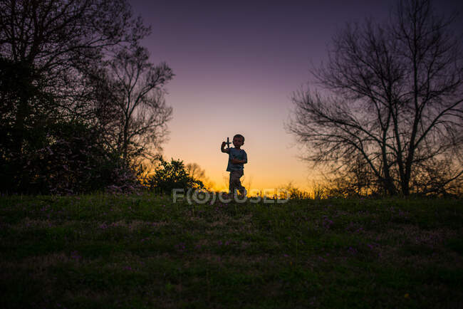 Kleiner Junge spielt Flugzeug Silohette Sommer Sonnenuntergang lila gelb — Stockfoto