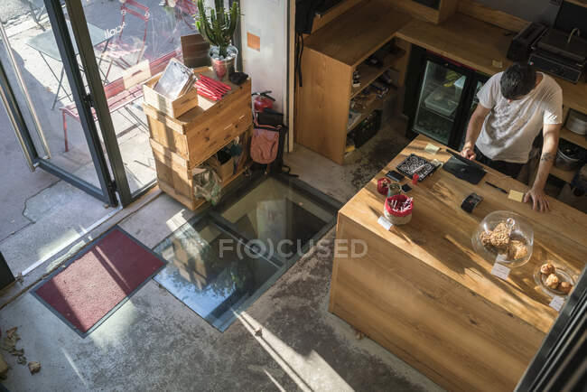 Lavoratore in un caffè alla moda con interni in legno — Foto stock