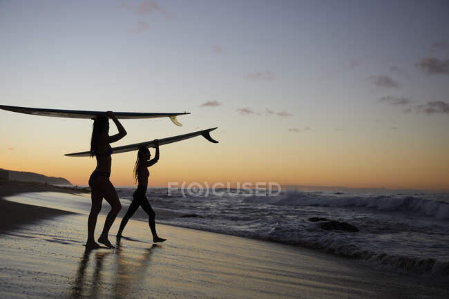 Niñas remando hacia Sunset Surf en la costa norte de Hawaii - foto de stock