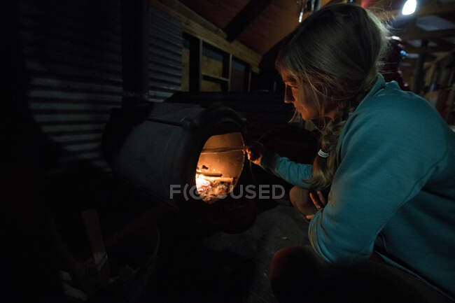 A woman tending to the fire in a backcountry ski yurt. — Stock Photo