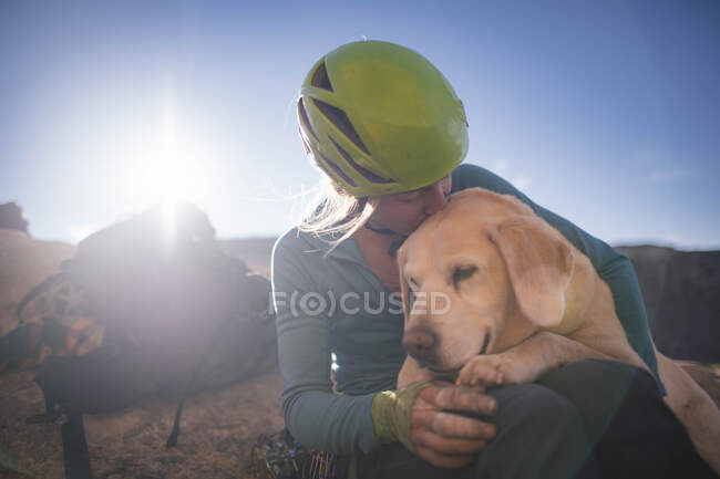 Una mujer dando a su perro un beso amoroso. - foto de stock