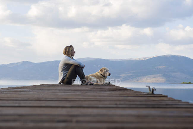 Una donna e il suo cane si godono una serata al molo sul lago di Hebgen. — Foto stock