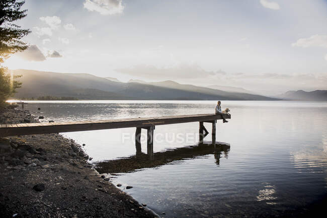 Une femme et son chien profitent d'une soirée sur les quais du lac Hebgen. — Photo de stock