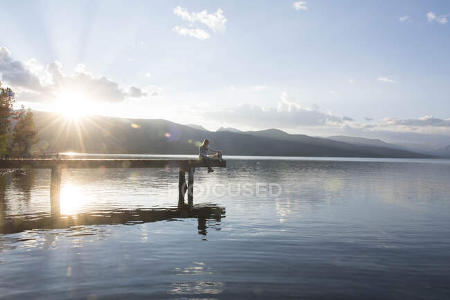 Una donna e il suo cane si godono una serata al molo sul lago di Hebgen MT — Foto stock