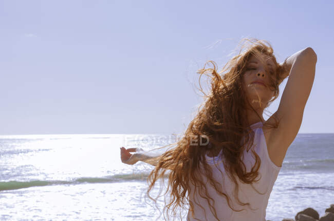 Femme aux cheveux rouges sur la plage venteuse — Photo de stock