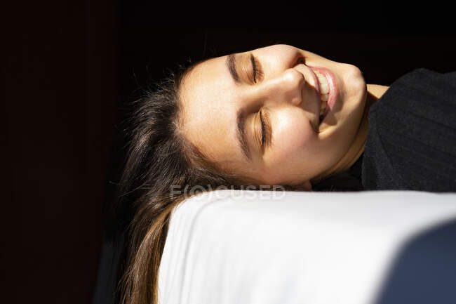 Frau sonnt sich auf weißem Bett. — Stockfoto